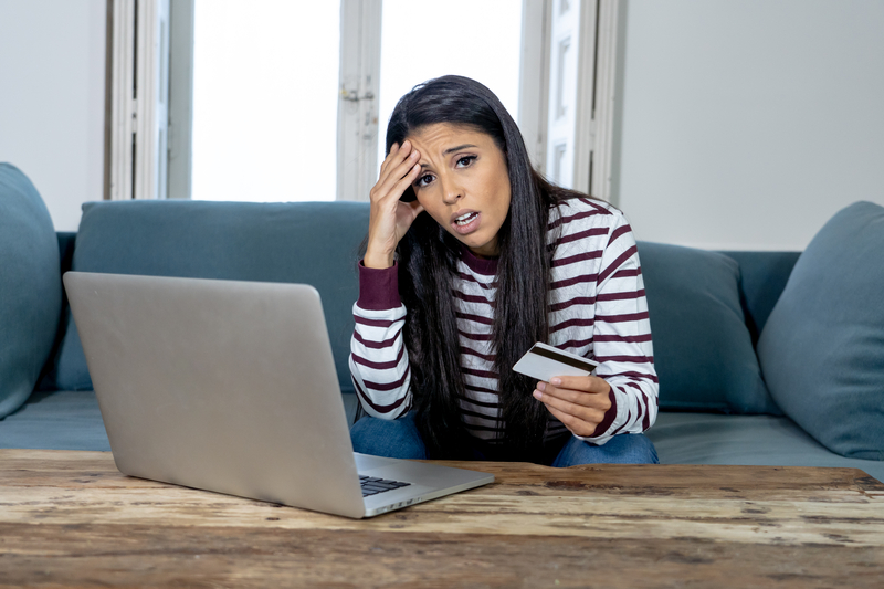Young woman using laptop angry and stressed about her credit card bill